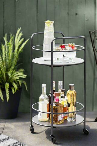 Gorgeous grey drinks trolley in an outdoor courtyard. The outdoor drinks trolley is loaded with booze bottles, a jug of margarita and wine glasses.