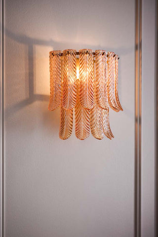 Lifestyle image of the Plume Glass Flush Wall Light displayed illuminated on a neutral wall. 