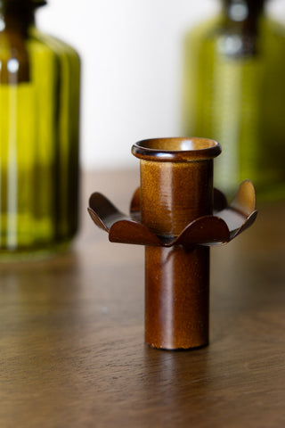 The brown bottle candle holder on a wooden surface. In the background you can see green bottles.