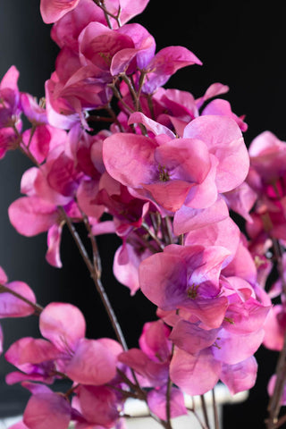 Detail of the fuchsia blossom stem. The faux plant is a vibrant hot pink and you can see the detail of the petals.