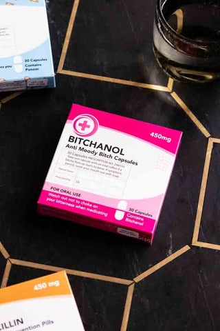 The Bitchanol Mints Pill Packet styled on a dark surface with some other boxes.