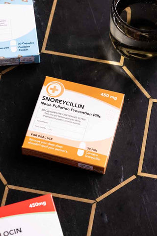 The Snoreycillin Mints Pill Packet styled on a dark surface with some other boxes.