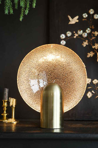Lifestyle image of the Glass Circle Table Light displayed on a black sideboard and surrounded by decorative accessories.