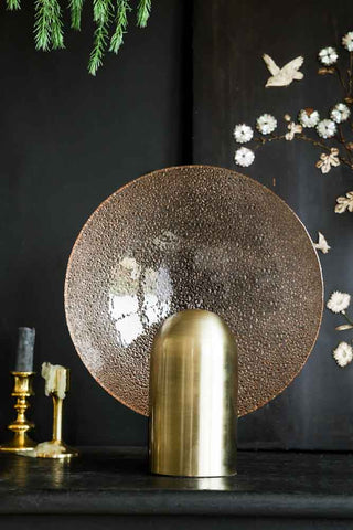 Lifestyle image of the Glass Circle Table Light displayed on a black sideboard styled with other home accessories. 
