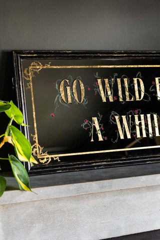 A close up image of the detailing on a rectangular mirror with the words 'Go Wild' on it.