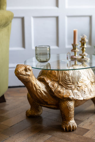 The Gold Tortoise Side Table seen from the side, styled with candles on top