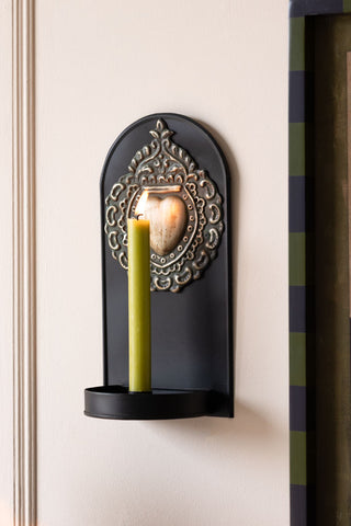 The Gold Milagro Heart Candlestick Wall Sconce on the wall, styled with a lit candle.