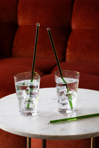 Three Green Glass Cocktail Stirrer styled in glasses in a art deco setting.