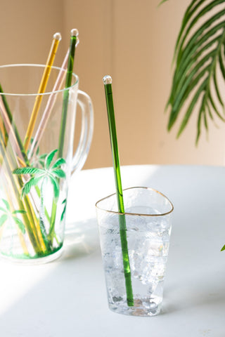 Green Glass Cocktail Stirrer in a glass of gin on a sunny table.