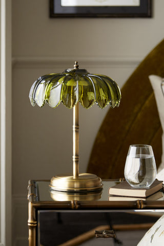 Lifestyle image of the Gold & Green Desert Table Lamp displayed on a mirrored side table with a book and a drinking glass
