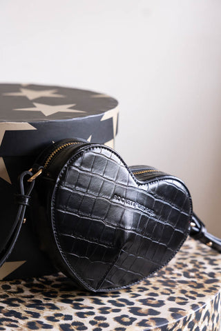 A black heart-shaped bag styled on a leopard print box.