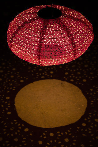The Hot Pink Hanging Outdoor Solar Lantern lit up in the dark.
