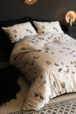 The Jane's Rose Duvet Cover and Pillow Set styled on a bed against a black wall.