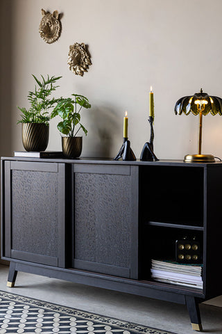 The Large Black Leopard Print Sideboard with plants, candles, a lamp and books on, with some other accessories inside/on the wall.