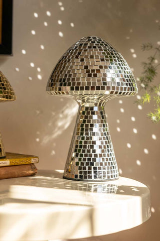 The Large Disco Mushroom Ornament displayed on a table in the sunshine, reflecting light onto the wall behind.