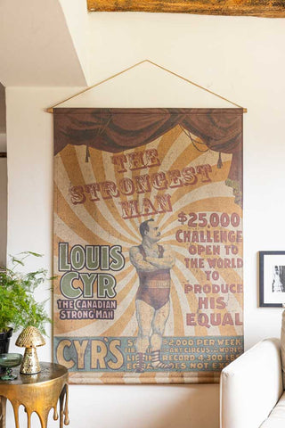 The Large Vintage-Style World's Strongest Man Wall Art displayed on the wall of a living room.