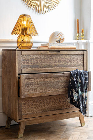 The Leopard Print Chest of Drawers with one drawer open and some clothing draped across it, with various accessories on the top.