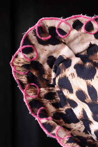 Detail shot of the corner of the Leopard Print Cushion With Pink Scalloped Edge.