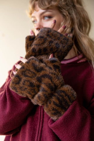 The Leopard Print Faux Fur Handwarmers being worn by a model with their hands up to their face.