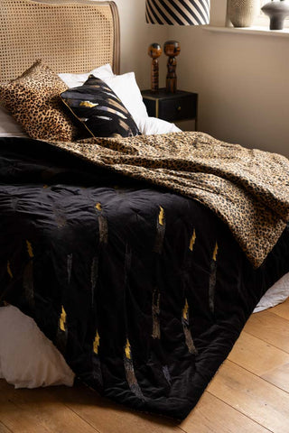 A styled image of the Reversible Black Lovestruck & Leopard Print Blanket on a wooden head board.