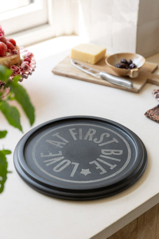 A styled image of the Marble Cheese Board on a kitchen worktop with cheese in the background.