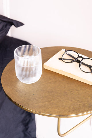 Close-up of the Metal Table & Wall Shelf styled as a bedside table, with a water glass, book and pair of glasses on.
