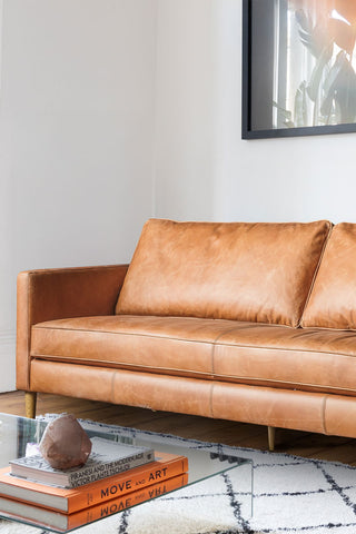 Close-up of one end of the Mid-Brown Vintage-Style Leather 3-Seater Sofa, styled on a rug next to a coffee table.