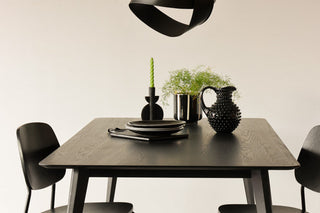 Landscape lifestyle image of the Black Dining Table against a white background