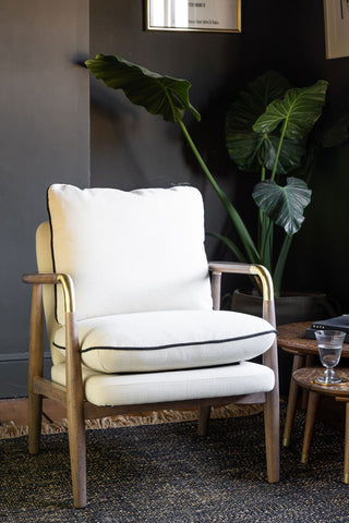 Natural armchair with wooden frame in a room with dark walls and a plant.