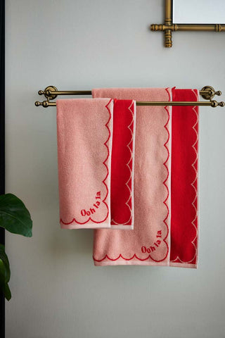 The Ooh La La Bath Towel and Ooh La La Hand Towel displayed on a towel rail on a bathroom wall, with a mirror and plant.