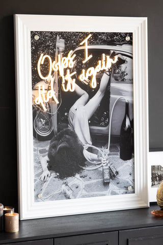 The Oops I Did It Again...Framed Neon Wall Light with a white frame styled on a black sideboard.