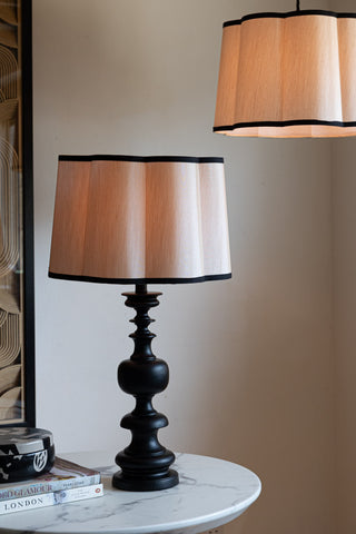 Two Oyster Scalloped Easyfit Lampshades, one styled as a pendant light and the other on a lamp base on a marble table, both with bulbs illuminated inside.