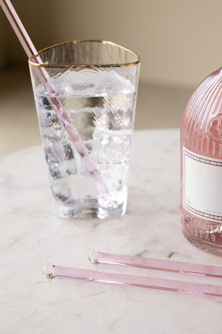 Pink Glass Cocktail Stirrer styled on a a marble surface with two Pink Glass Cocktail Stirrer's lying down.