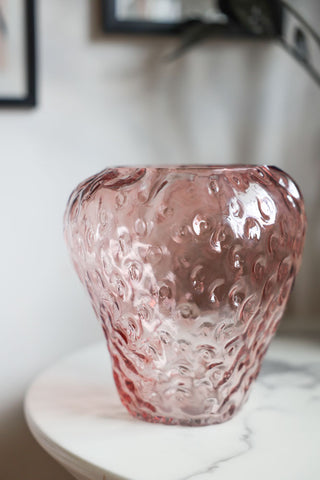 Lifestyle image of the Pink Strawberry Glass Vase displayed on a white marble table. 