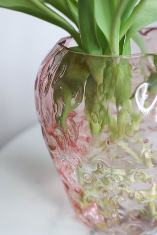 Lifestyle image of the Pink Strawberry Glass Vase displayed with flowers inside. 