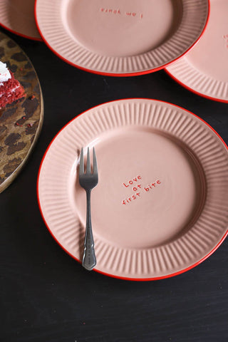 The Pink & Red First Bite Side Plates displayed on a black table with other kitchen accessories.