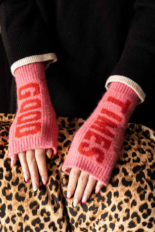The Pink & Red Good Times Handwarmers being worn by a model with their hands resting on a leopard print chair.
