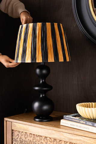 The Raffia Black & Natural Stripe Easyfit Lampshade shown on a wooden background.