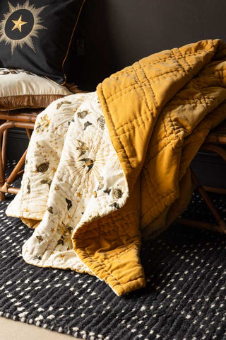The Reversible Gold Rock & Rose Blanket draped over a bench.