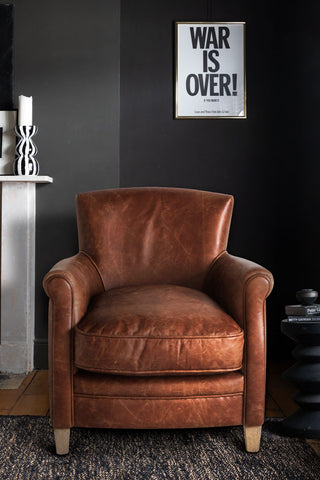 The Rich Brown Vintage-Style Leather Armchair styled in a living room on a rug.