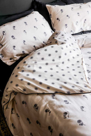 A styled image of the Rock & Rose Duvet Cover & Pillow Case Set on a bed against a black wall.