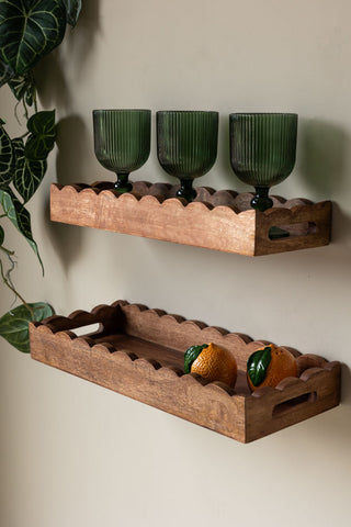 The Set Of 2 Natural Wooden Scalloped Wall Shelves styled on a light wall with various kitchen accessories on and a plant hanging down