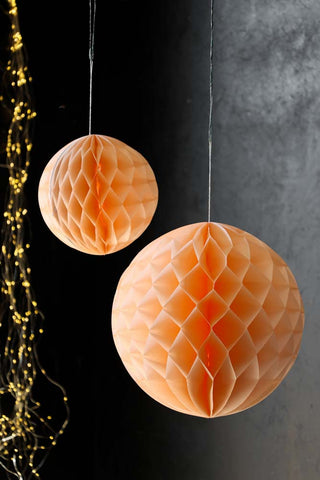 Lifestyle image of the Set Of 2 Peach Honeycomb Ball Decorations