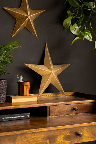 Lifestyle image of the Set Of 3 Antique Gold Metal Stars on desk