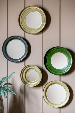 The Set Of 5 Metal Frame convex mirror set in Green & Natural displayed on a neutral wall above a potted plant.