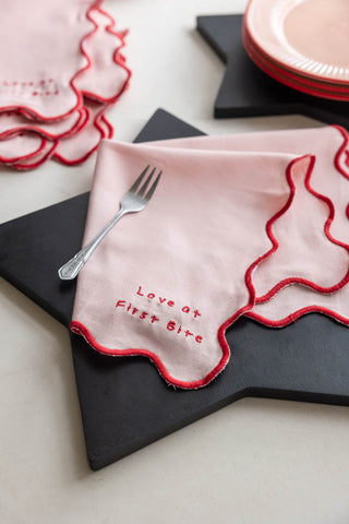 One of the Set of 4 Pink & Red First Bite Napkins styled on a black star chopping board