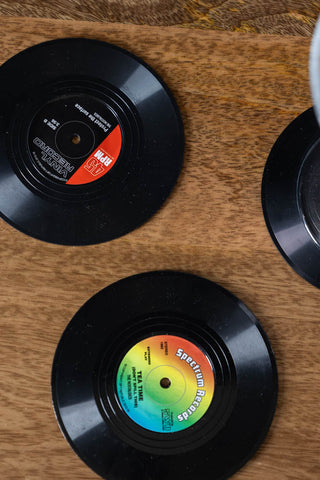 Three of the Set of 6 Vinyl Style Coasters displayed on a wooden table.