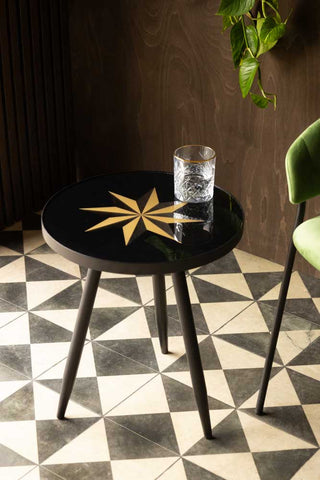 Lifestyle image of the Small Black Star Side Table styled with glass on top
