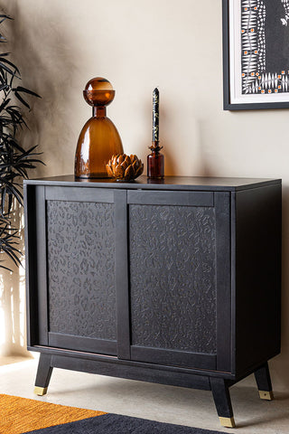 The Small Black Leopard Print Sideboard styled with some accessories on, next to a plant, rug and art print.