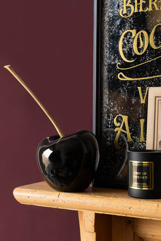 Image of the Small Cherry Ornament on fire place against a burgundy background.